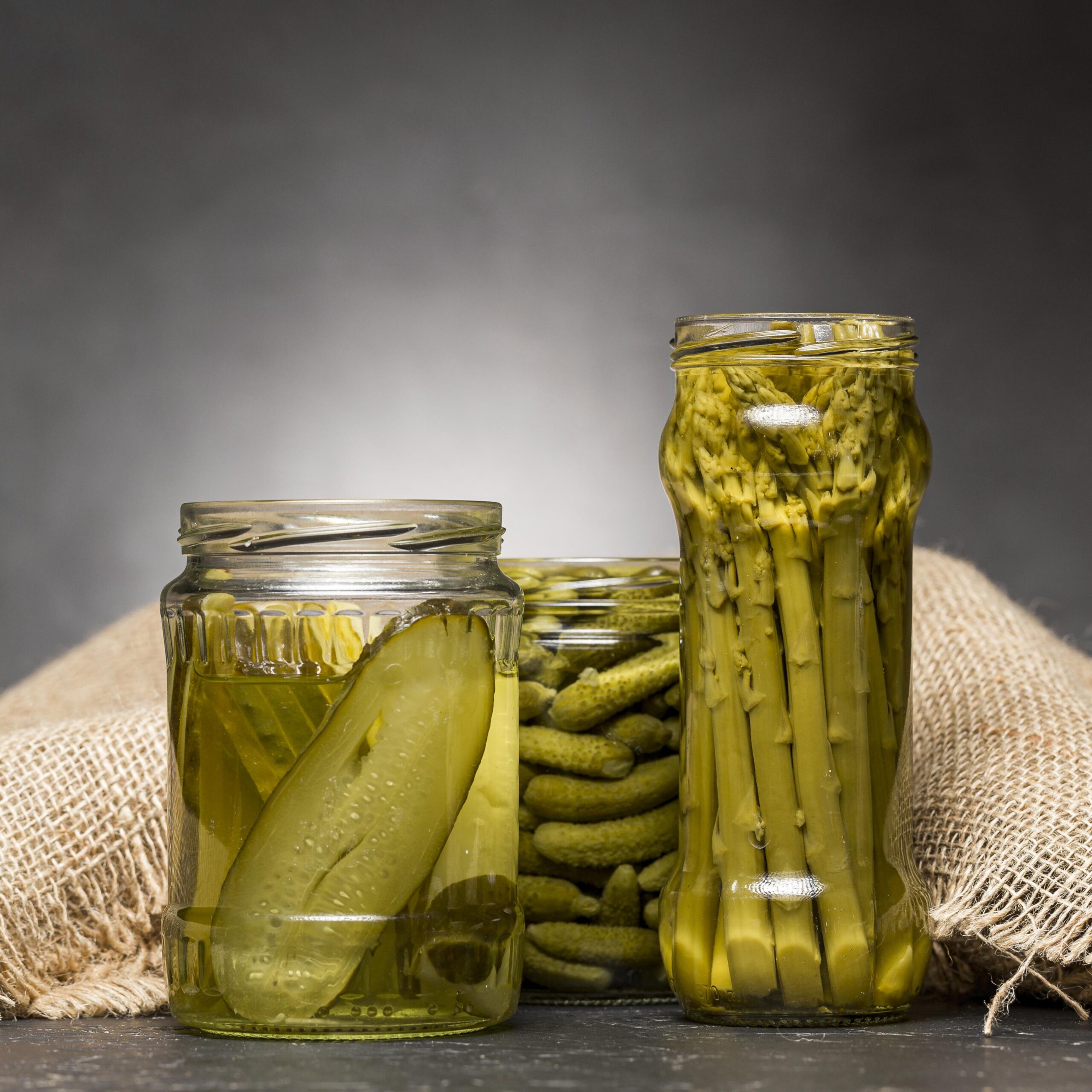 front view glass jars with pickled asparagus cucumbers scaled